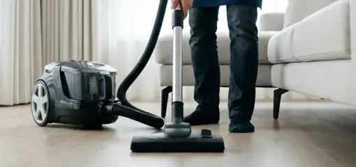 Professional house cleaner vacuuming a living room floor with a canister vacuum cleaner, Saint Louis, MO.