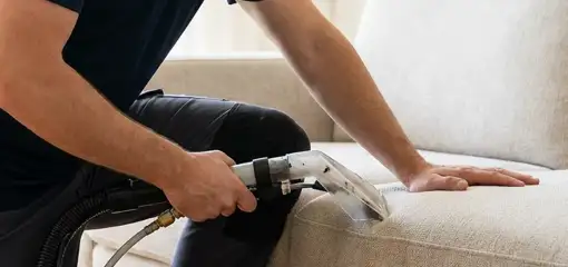 Professional upholstery cleaner deep-cleaning a fabric sofa with a handheld extraction tool, Saint Louis, MO.